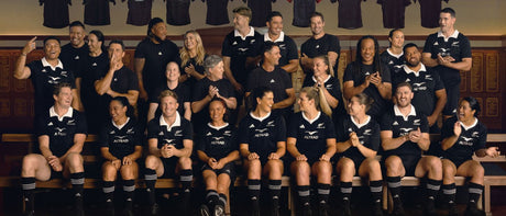 Rugby player in all blacks jersey catching a rugby ball.