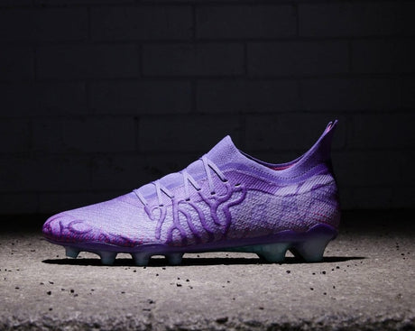 A single purple soccer cleat against a brick wall background, highlighted by dramatic lighting.