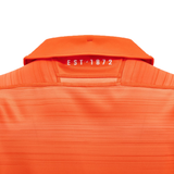 The vibrant orange shirt, known as the Edinburgh Replica Away Jersey 24/25 by Macron, is shown from the back with "EST 1872" prominently featured beneath the collar.