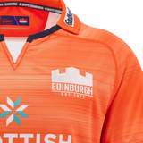 Close-up of an orange Edinburgh Replica Away Jersey 24/25 by Macron, featuring white logos and text that reads "Edinburgh Est. 1872.