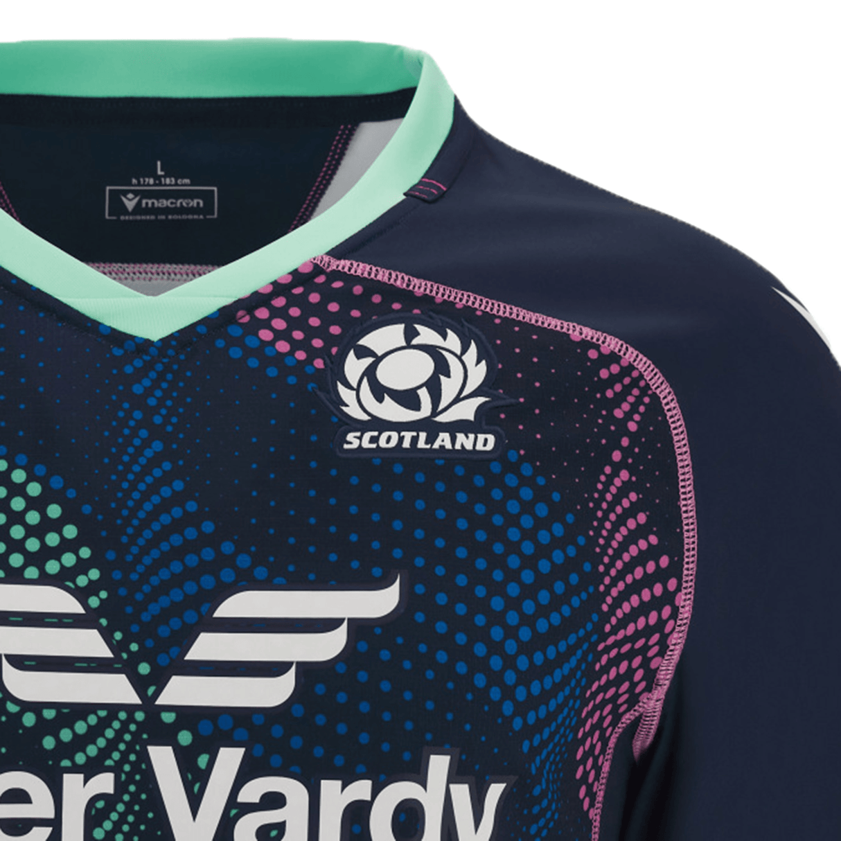 A close-up of the Scotland Rugby Union Training Jersey 23/24 by Macron, featuring the iconic logo on the chest. The training shirt showcases a dark blue base with teal and pink accents and is made by Macron.