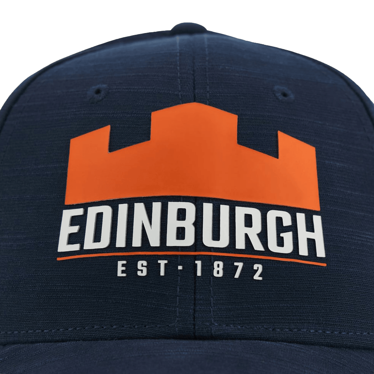 Close-up of a navy blue polyester Edinburgh Cap 23/24 by Macron with an orange and white logo representing "Edinburgh est. 1872" on the front.