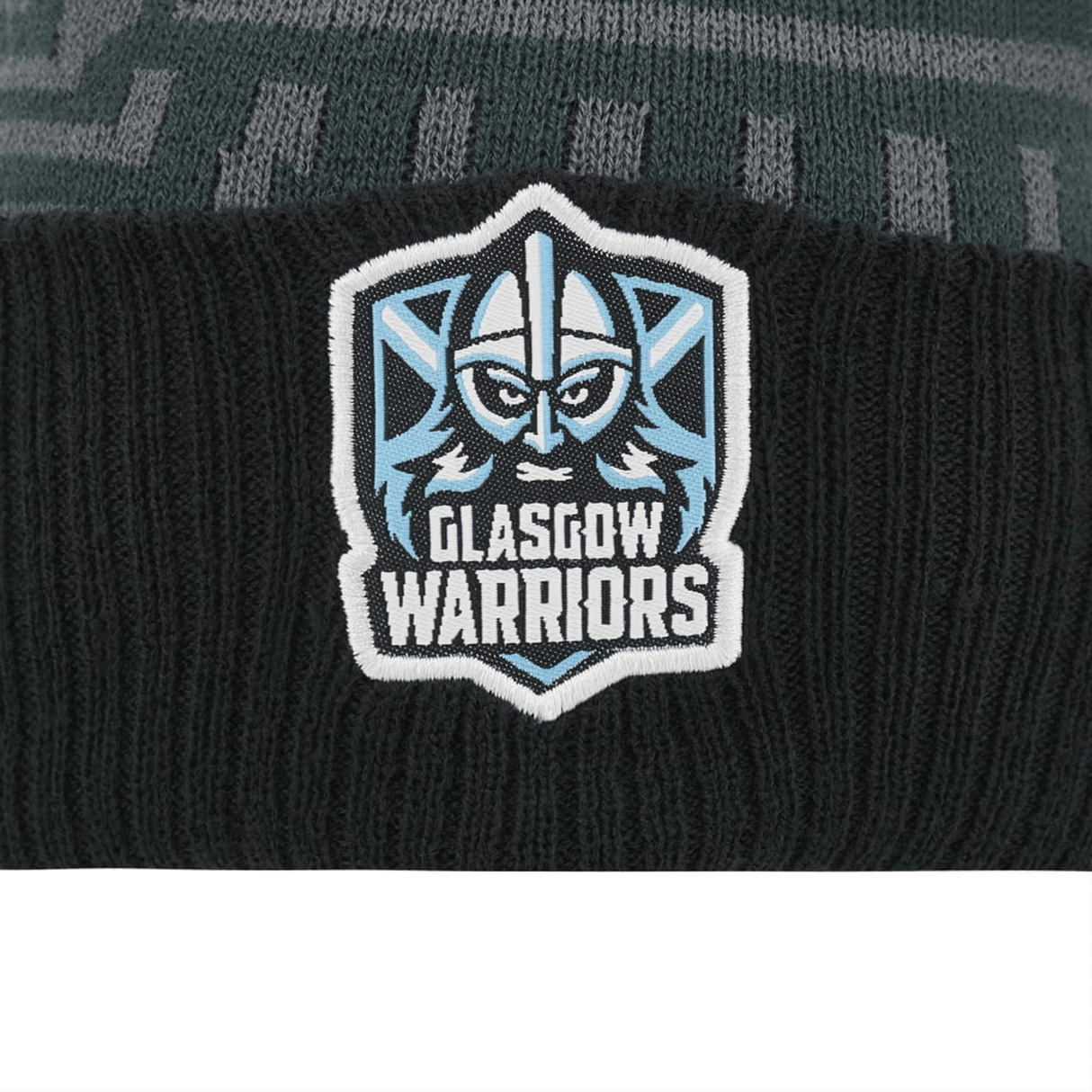 Close-up of a Glasgow Warriors Beanie 23/24 logo patch on a knitted polyester fabric, featuring a stylized warrior face in blue and white by Macron.