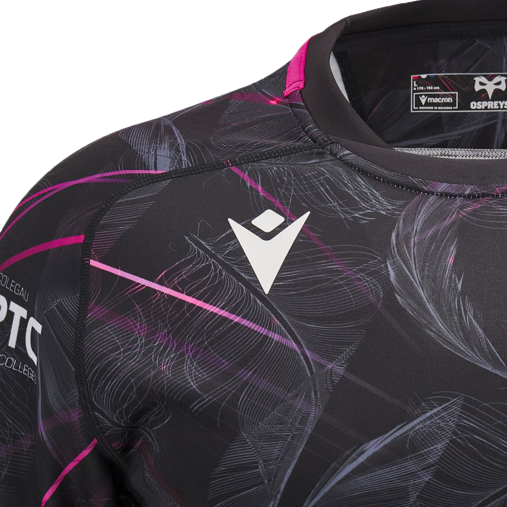 Close-up of the Ospreys Rugby 24/25 Poly Cotton T-Shirt by Macron in black, showcasing abstract pink and white patterns. It boasts a white geometric logo on the chest, capturing the dynamic spirit reminiscent of Ospreys Rugby attire.