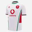 The Wales 24/25 Replica Away Jersey by Macron boasts striking red and green details on a pristine white background, highlighting the distinctive Welsh Rugby Union logo alongside Vodafone branding. Designed by Macron, it captures the essence of rugby with style and authenticity.