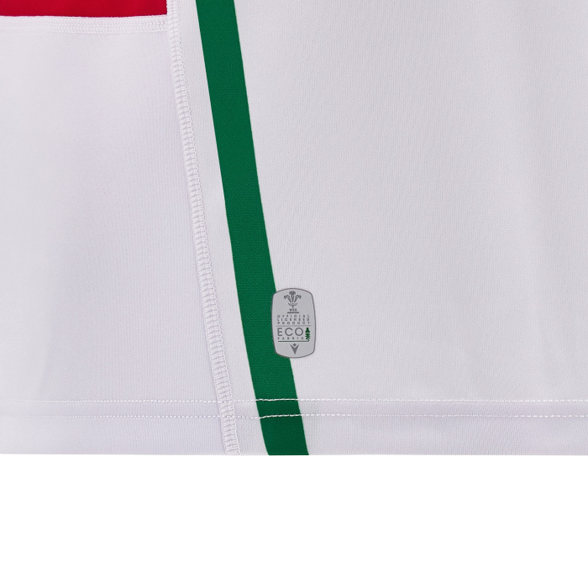 Detailed view of the Wales 24/25 Replica Away Jersey by Macron, highlighting a vertical green stripe and a touch of red rectangle on the white fabric. A small "Made with EcoY" logo is present near the bottom center, emphasizing its eco-friendly aspect within the sporty design.