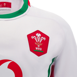 The Wales Rugby Union 24/25 Replica Away Jersey by Macron showcases a white design with red and green accents, featuring a bold red emblem of three feathers coupled with the "WRU" letters.