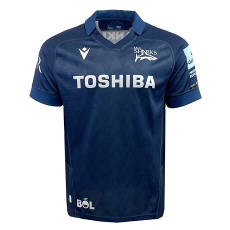 The Sale Shark Rugby 24/25 Home Jersey by Macron is a navy blue rugby jersey featuring the "Sale Sharks" and "Toshiba" logos, complemented by a subtle chevron pattern.