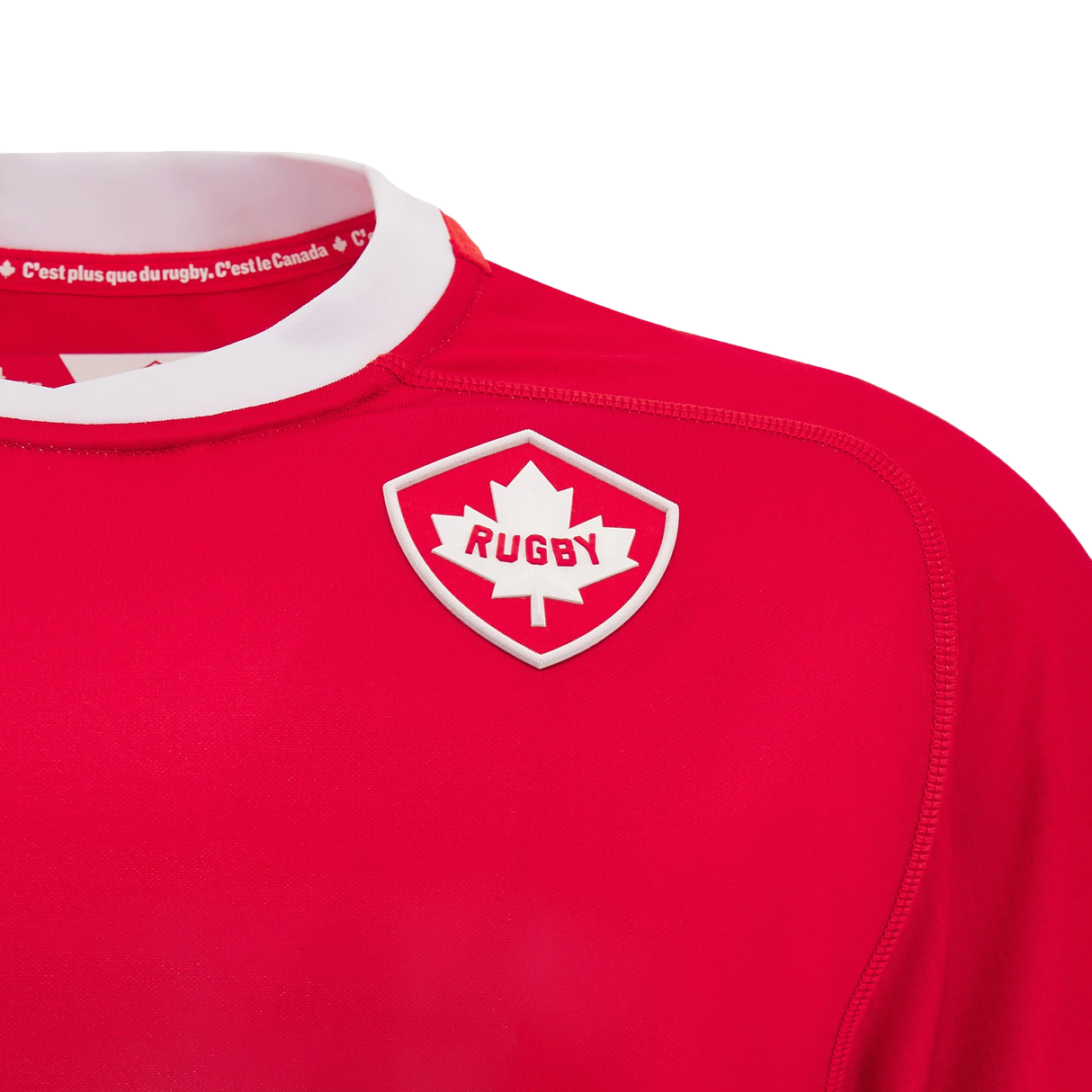 Introducing the Canada 24/25 Home Jersey by Macron: a bold red rugby jersey featuring a white collar adorned with bilingual text and a maple leaf patch labeled "Rugby." Just in, this jersey embodies national pride and sporting spirit.