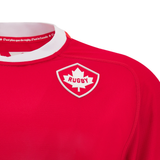 Introducing the Canada 24/25 Home Jersey by Macron: a bold red rugby jersey featuring a white collar adorned with bilingual text and a maple leaf patch labeled "Rugby." Just in, this jersey embodies national pride and sporting spirit.