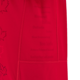 Close-up of a red fabric with faint text listing Canadian provinces, reminiscent of the Canada 24/25 Home Jersey by Macron.