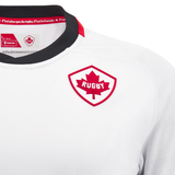 The Canada 24/25 Away Jersey by Macron presents a white rugby jersey adorned with a red and white maple leaf emblem on the chest. It highlights a black collar with a red accent, and inside, it features the text "C'est plus que du rugby: C'est le Canada.