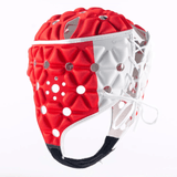 The Gilbert Air Headguard, a padded athletic helmet featuring white laces and hexagonal cutouts on its red and white surface, is designed for superior head protection. This helmet ensures enhanced shock absorption while remaining lightweight.