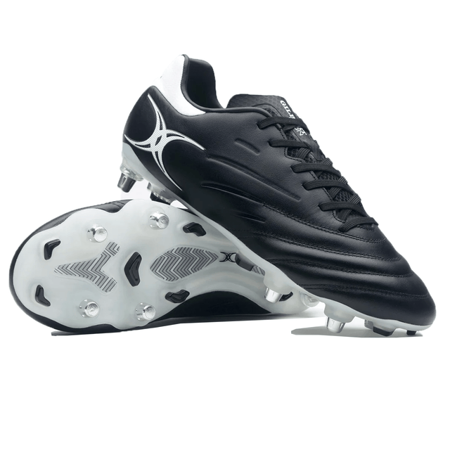 A pair of Gilbert Icon 6S SG - Black soccer cleats. One shoe stands upright, while the other lies on its side, highlighting the studded sole. Perfect for performance on soft ground, these cleats feature an iconic design reminiscent of traditional rugby boots.