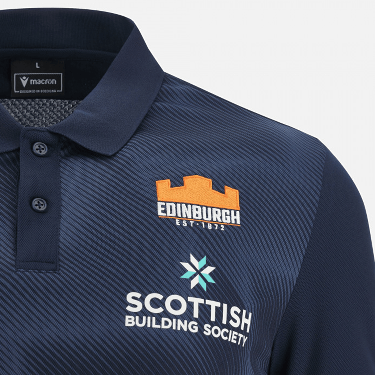 Close-up of a navy Edinburgh Rugby 23/24 Player Travel Polo featuring the Edinburgh Rugby logo and Scottish Building Society sponsorship, by Macron.