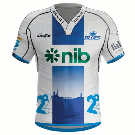 The Blues Super Rugby Away Jersey 24 by Classic Sportswear is a white and blue sports jersey featuring logos like "nib" and "Blues," with Blue stripes and a city skyline design. Made with Stay Cool tech fabric, it keeps you comfortable while supporting the team.