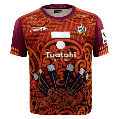 The Gallagher Chiefs Super Rugby Training Jersey 24 by Classic Sportswear features Maori-inspired patterns and designs in dominant orange and maroon colors, showcasing the team name "Chiefs" and sponsor logos "Tuatahi First Fibre" on the front. Made from anti-microbial wickable fabric, this jersey from Classic Sportswear ensures comfort during intense training sessions.