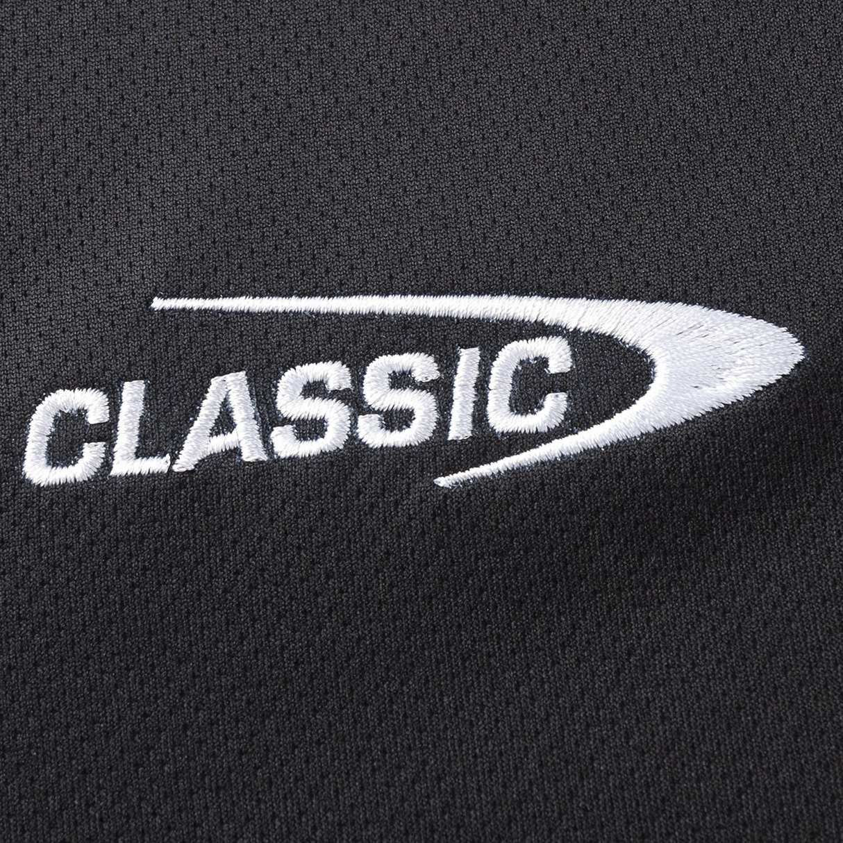 Close-up of white "CLASSIC" embroidery with a curved line on black, moisture-wicking fabric, evocative of the Crusaders Super Rugby Team Polo 25/26 by Classic Sportswear.