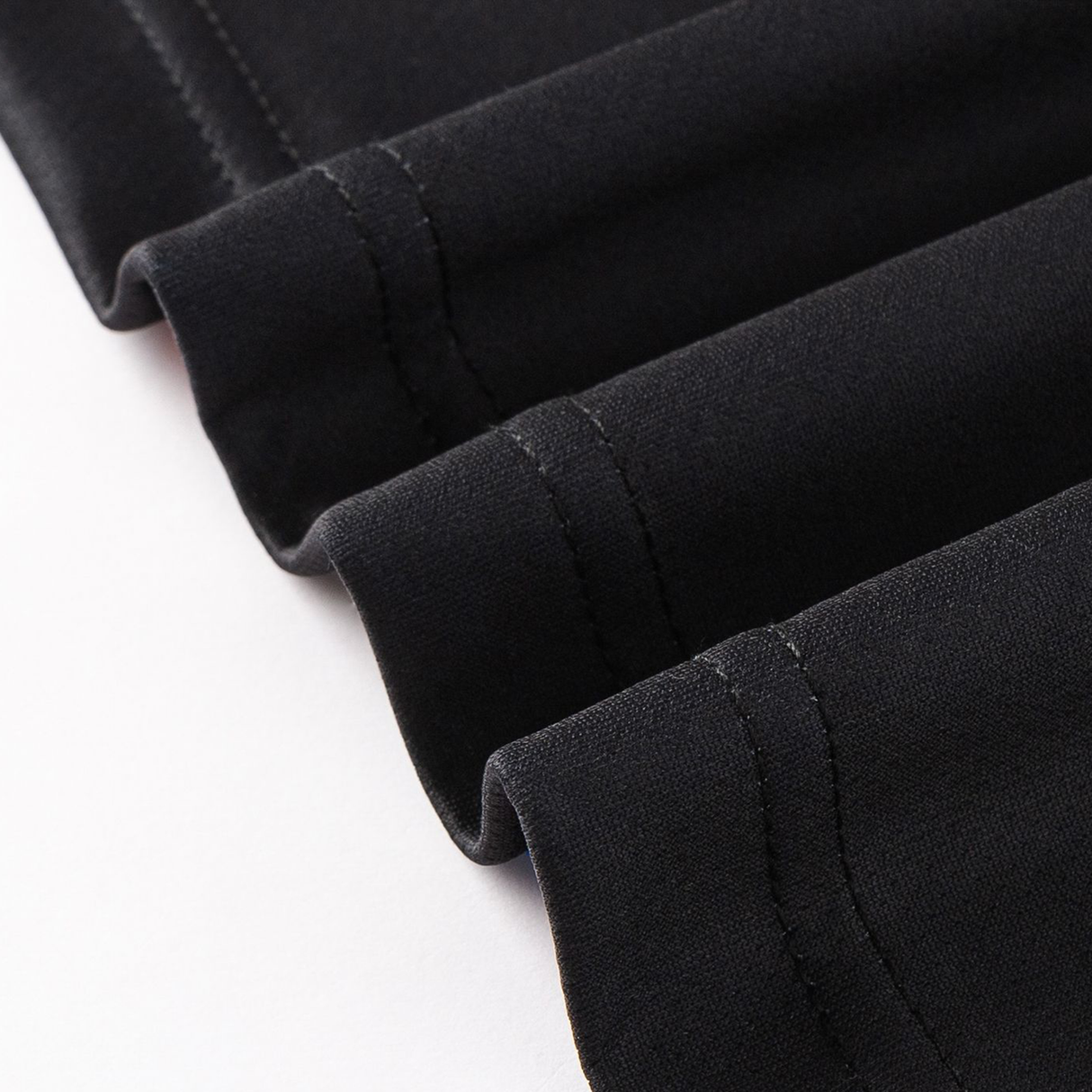 Close-up of black moisture-wicking fabric folds with visible stitching, showcasing details typical of the Crusaders Super Rugby Team Polo 25/26 by Classic Sportswear.