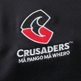 Close-up of a Crusaders Super Rugby Team Polo 25/26 by Classic Sportswear, featuring black moisture-wicking fabric with an embroidered stylized "C," "Crusaders" text, and the phrase "Mā Pango Mā Whero" beautifully stitched beneath.