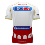 Back view of the Dolphins NRL Heritage Jersey by Classic Sportswear featuring BlueBet and AngloAmerican logos, with the hashtag "#PHINSUP" on the upper back. The lower half showcases a red design resembling tree or roof silhouettes and text "DOLPHINS." Crafted by Classic Sportswear, it's a nod to ANZAC Avenue's legacy.