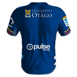 The image showcases the back of the Highlanders Super Rugby Home Jersey 24 by Classic Sportswear, prominently displaying the University of Otago logo along with sponsor logos from Pulse Energy, Forsyth Barr, and others. Predominantly blue with colorful accents on the sleeves, this Classic Sportswear jersey is poised to make a statement in Super Rugby 2024.