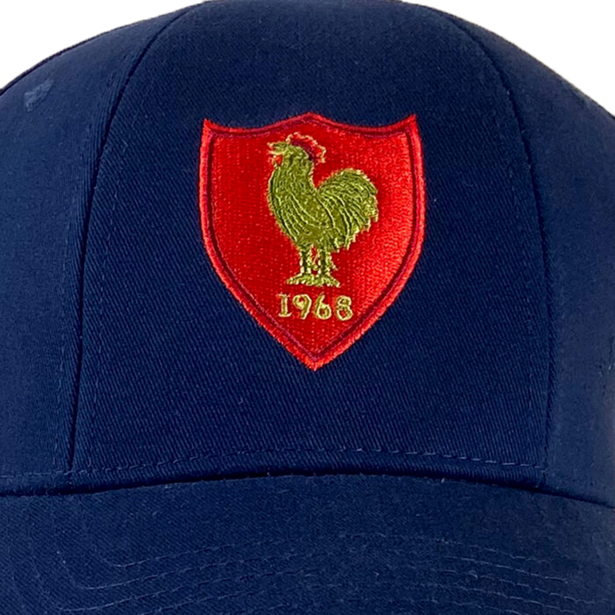 The France Rugby 1968 Grand Slam Cap by Ellis Rugby features a blue design with a red and yellow emblem of a rooster and the year 1963, capturing the essence of French rugby spirit. Reflecting Ellis Rugby's classic designs, this cap embodies the spirit witnessed in legendary matches like their Grand Slam victory.