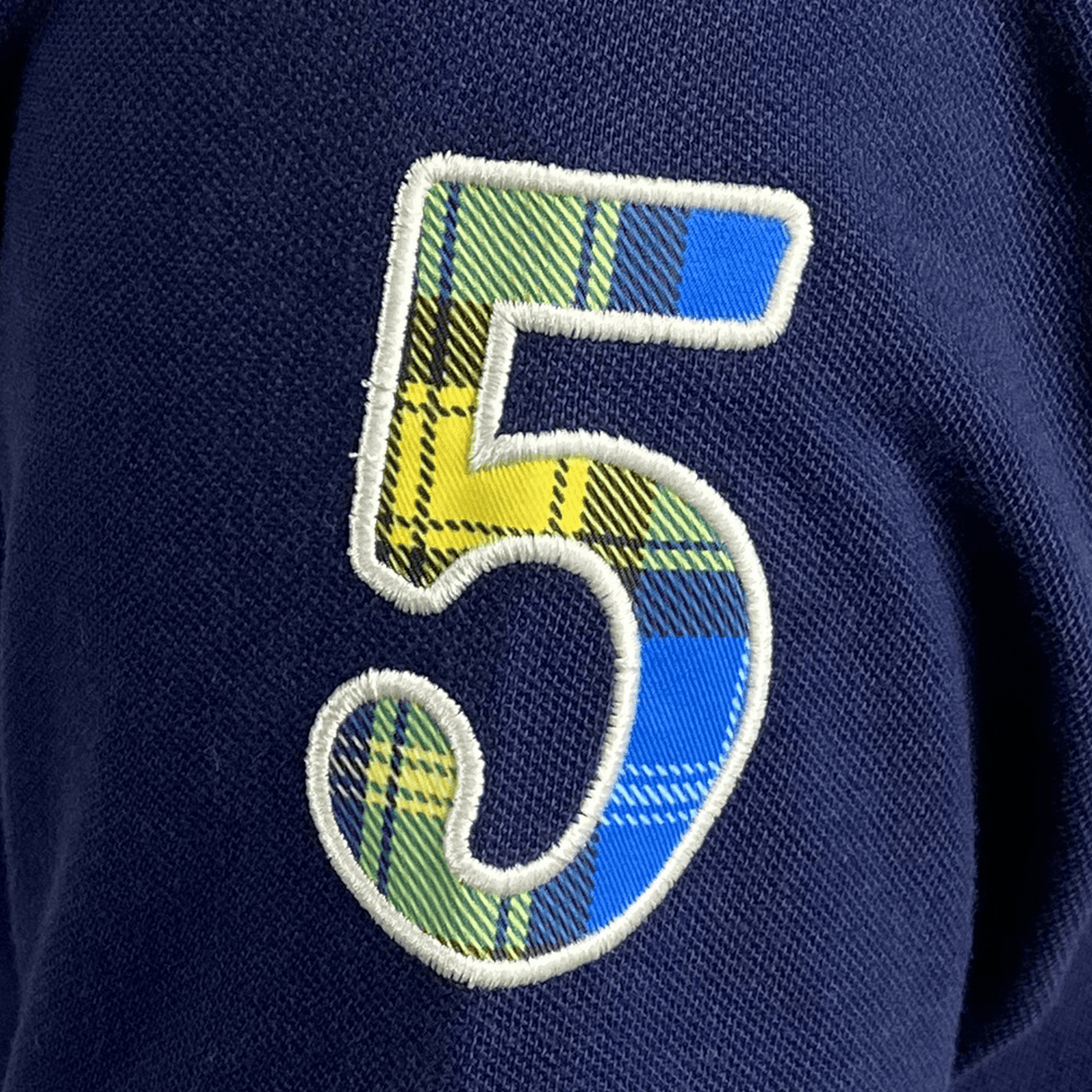 The number five on a Doddie Weir Polo by Ellis Rugby navy polo shirt.