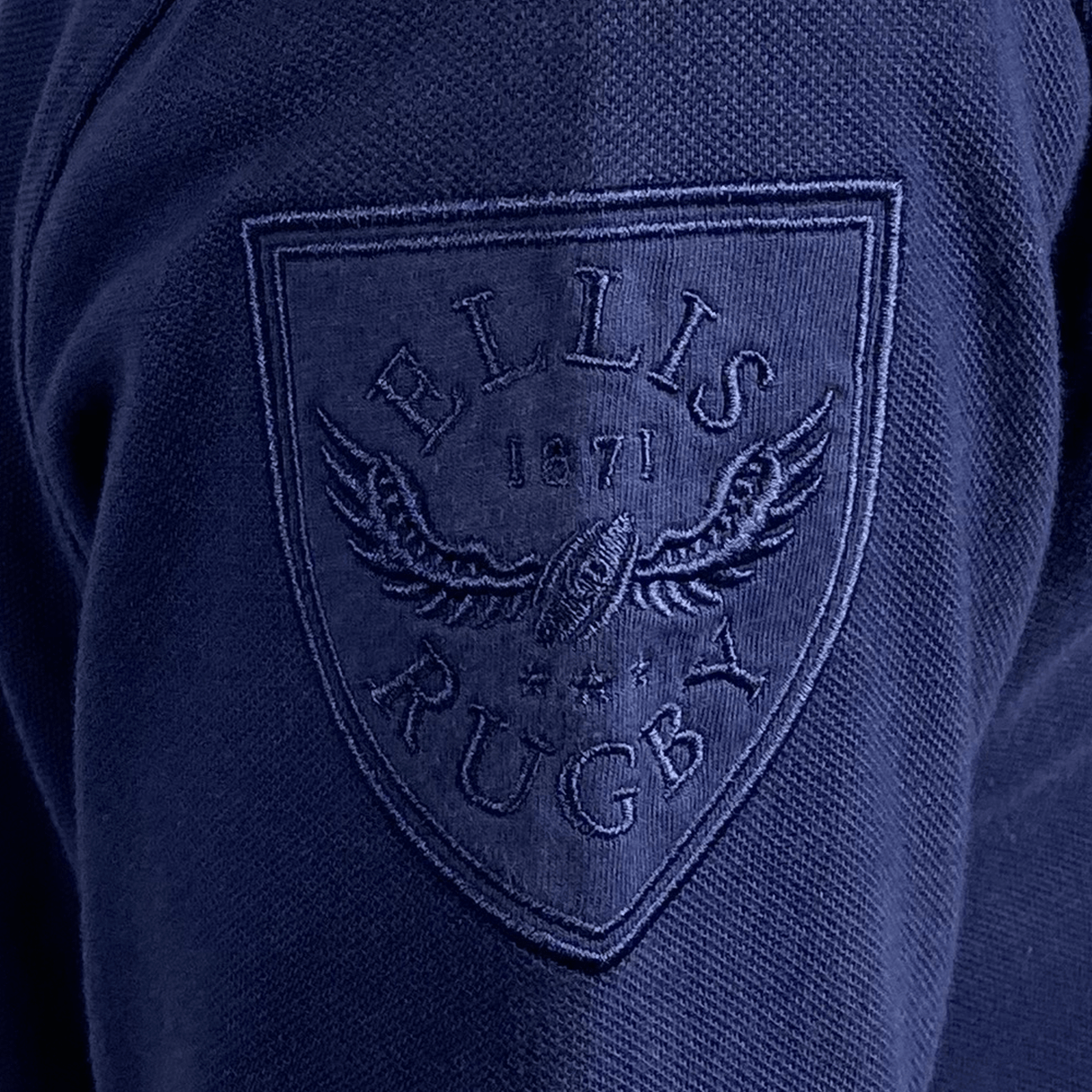 The back of a blue Doddie Weir Polo by Ellis Rugby with the Ellis Rugby logo on it.