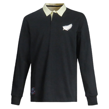 The All Blacks 1983 Classic Rugby Shirt by Ellis Rugby boasts a black long-sleeve design with a beige collar and a white fern emblem on the chest, capturing the spirit of the All Blacks and offering timeless elegance for Ellis Rugby fans.