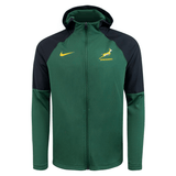 The Springboks Full Zip Training Hoodie 23/24 by Nike features a green and black design with a yellow Nike logo on the right chest and a Springboks logo on the left chest. This moisture-wicking hoodie combines team branding with performance, ensuring you stay comfortable while showing your support.