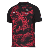 The Fiji 24/25 Replica Away Jersey by Nike is a striking black sports piece decorated with red palm leaf designs. It features the white "Fiji Airways" logos on the chest, making it an ideal rugby replica jersey for fans who value both style and functionality.