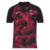 The eye-catching Fiji 24/25 Replica Away Jersey by Nike sports a vibrant black and red design accented with a palm leaf pattern, prominently displaying a logo featuring two crossed palms. Additional logos adorn the sleeves, enhancing this rugby replica jersey's dynamic and authentic appeal.