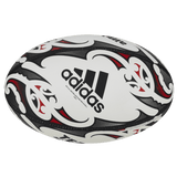 The All Blacks Replica Ball by adidas features a tribal-inspired black, red, and white pattern with the Adidas logo prominently displayed at the center. Its design is inspired by Maori patterns, capturing the bold essence of an adidas replica rugby ball.