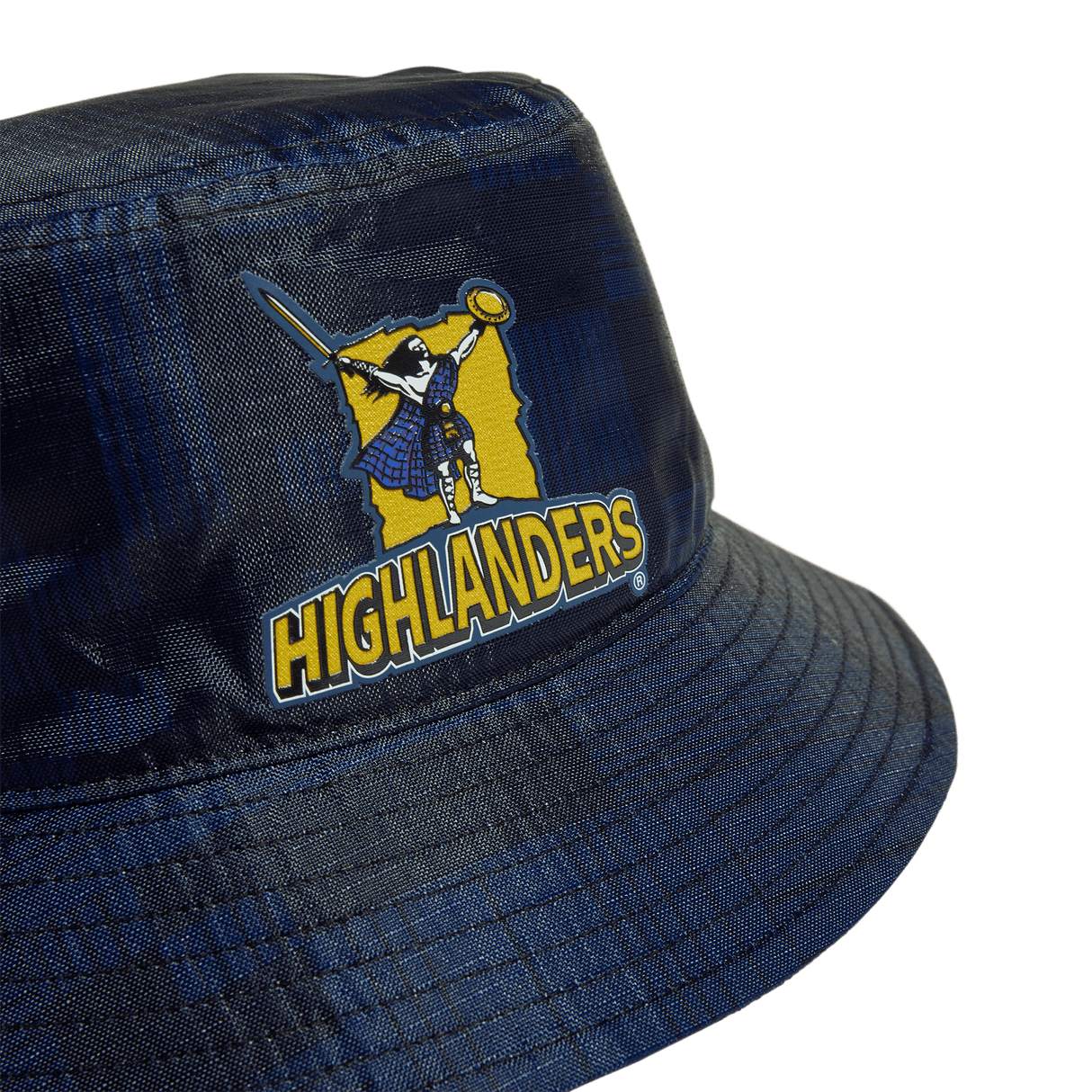 The Highlanders Super Rugby Bucket Hat by Adi COTW features a navy design adorned with adidas branding and a distinctive "Highlanders" logo portraying a kilted figure wielding a sword and shield, all set against a yellow and blue checkered backdrop. Ideal for Highlanders Super Rugby fans eager to display their team spirit with flair.