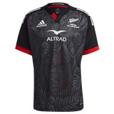 A Māori All Blacks Home Supporters Jersey by adidas, colored in black and red, crafted from recycled polyester, highlighting intricate designs and prominently displaying the Adidas and Altrad logos.