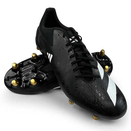 A pair of black soccer cleats with white stripes and gold studs, one positioned upright and the other lying on its side, showcasing the studded sole. These adidas adizero RS15 Pro SG 23 - Core Black/White/Carbon cleats are ideal for rugby on soft ground.