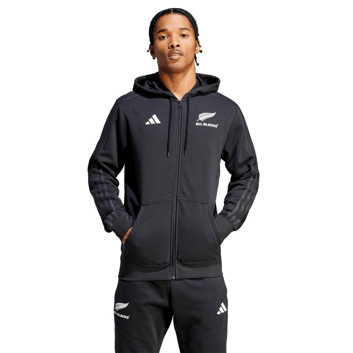 A person wearing the All Blacks Supporter Full-Zip Hoodie by adidas, crafted from French terry fabric, stands with hands in pockets, the adjustable hood pulled up over their head, and matching pants completing the look.