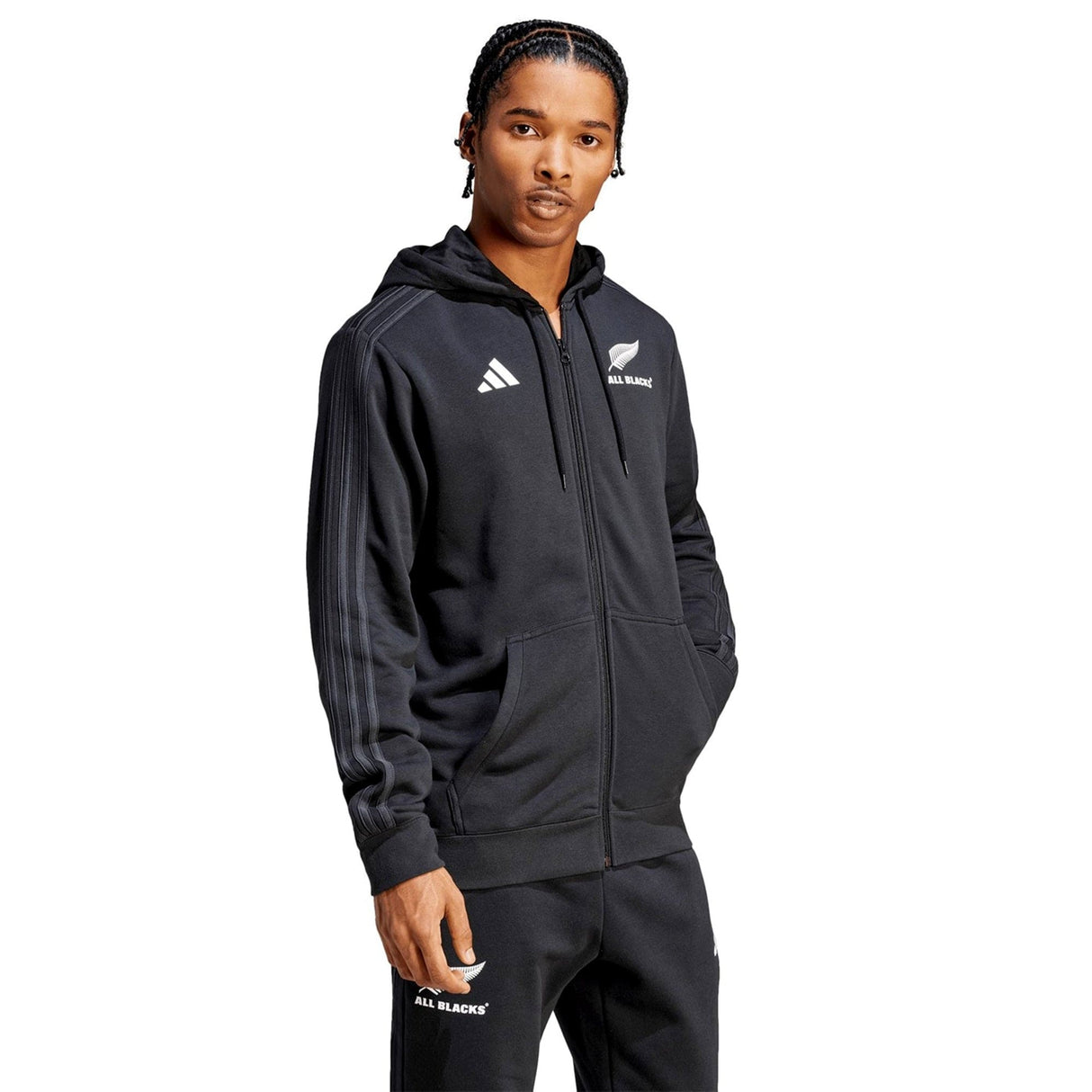 A person wearing an All Blacks Supporter Full-Zip Hoodie by adidas in black, made from soft French terry fabric, paired with matching pants, hands tucked into pockets, stands against a white background.