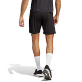 Back view of a person in black sports attire, including a short-sleeved shirt, adidas All Blacks Gym Short featuring moisture-wicking AEROREADY technology, and running shoes. They are walking away on a white background.