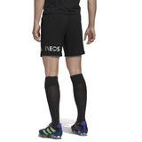 Rear view of a person in black sports attire, including an AEROREADY technology t-shirt, adidas All Blacks Home Short featuring "INEOS" printed on them, black knee-high socks, and cleats with a green, purple, and blue design, standing on a white background.