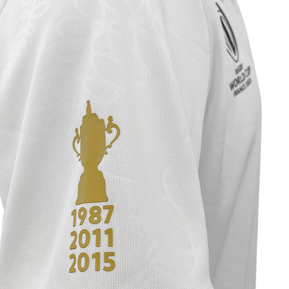 Close-up of the All Blacks RWC 23 Away Supporter Jersey by adidas showcasing a gold trophy icon with the years 1987, 2011, and 2015 printed below it. This replica match jersey is an essential for any fan preparing for RWC 2023.