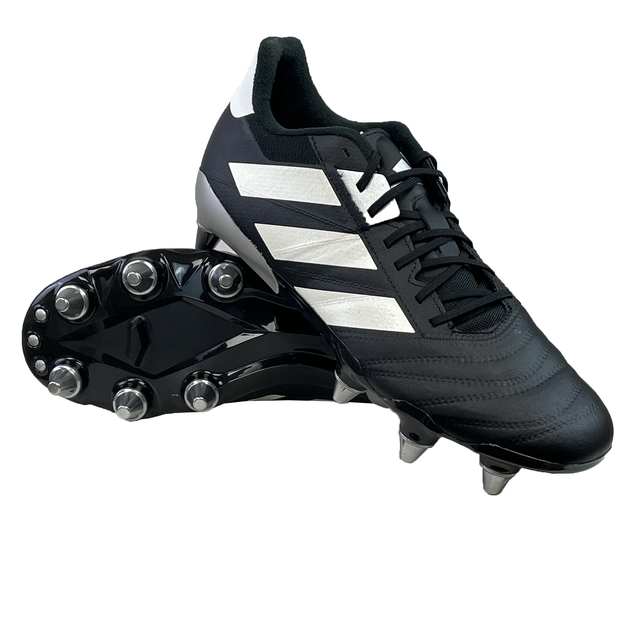 The adidas Kakari RS SG rugby boots in Core Black, Zero Metallic, and Gold Metallic boast a sleek design with a lightweight frame and metal studs, ideal for soft ground play. They are showcased on a pristine white background.