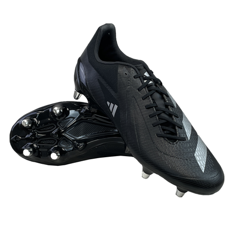 A pair of adidas Adizero RS15 Ultimate SG rugby boots in Core Black with Zero Metallic accents is on display, featuring the Speedframe outsole to enhance agility. One boot stands upright while the other lies on its side, effectively showcasing the studs.