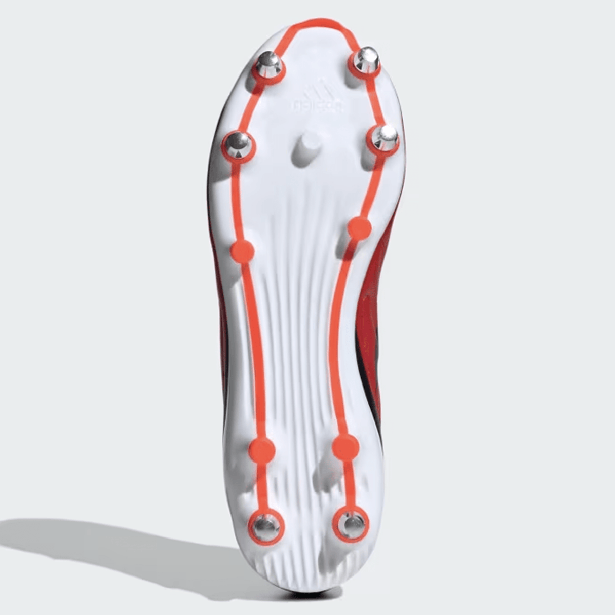 The image shows the bottom view of an adidas RS15 SG 24 Rugby Cleat in Better Scarlet, Core Black, and Solar Red. It features metal studs, a Speedframe outsole, and an orange outline design on the lightweight synthetic forefoot.