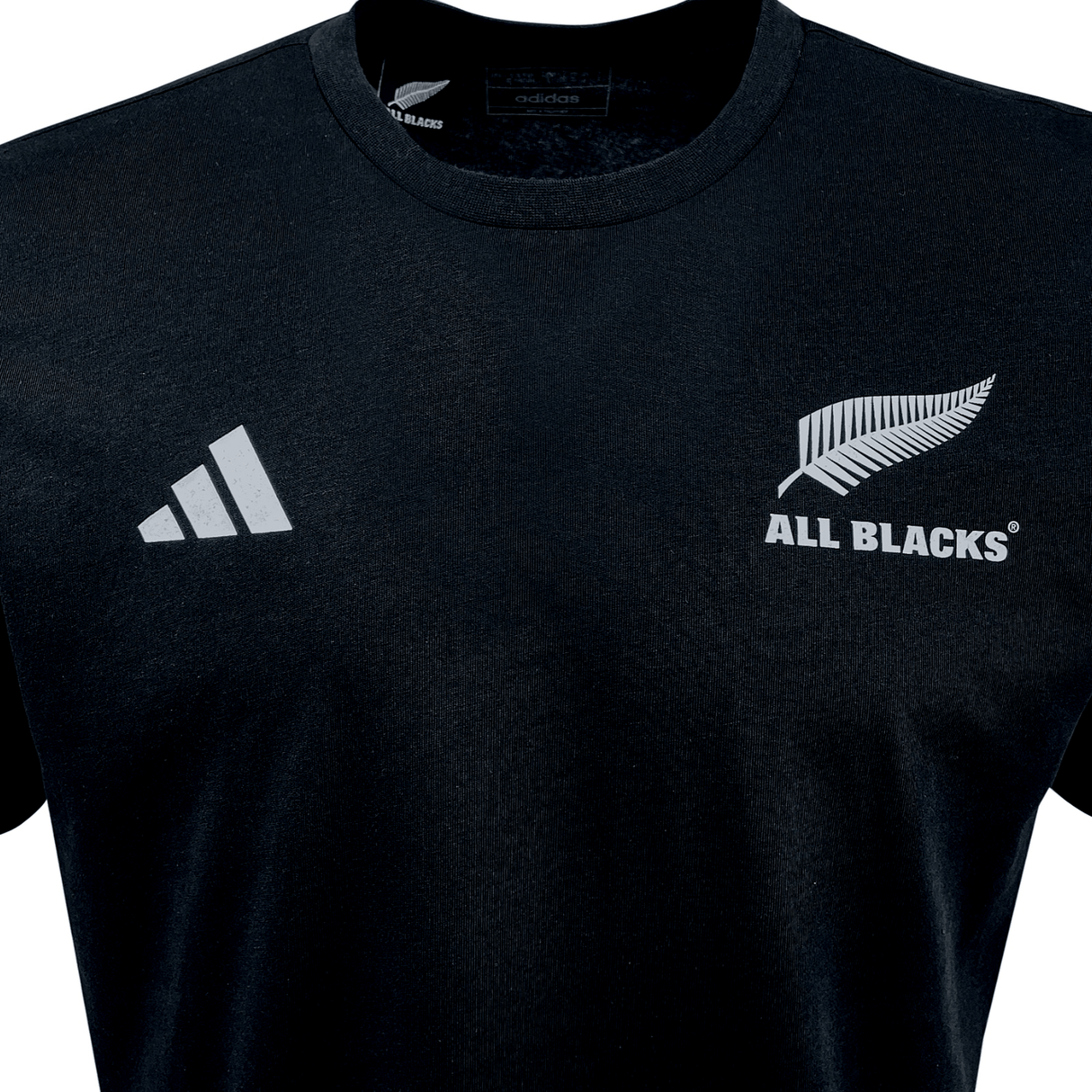 Sport the All Blacks Cotton Tee by adidas, featuring a black design with "ALL BLACKS" text and a silver fern logo on the right side. The iconic Adidas logo with three diagonal stripes adorns the left side. Celebrate New Zealand rugby with this authentic adidas T-shirt made for fans.