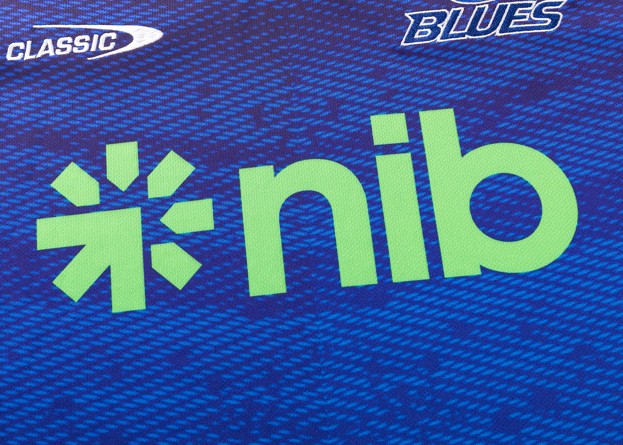 Close-up of a Blues Super Rugby 25/26 Replica Home Jersey by Classic Sportswear, showcasing logos for "Classic Sportswear," "Blues Super Rugby," and "nib" on a blue patterned background.