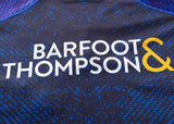 Close-up of the Blues Super Rugby 25/26 Replica Home Jersey by Classic Sportswear, featuring "BARFOOT & THOMPSON" text in white and yellow on a dark blue patterned background.