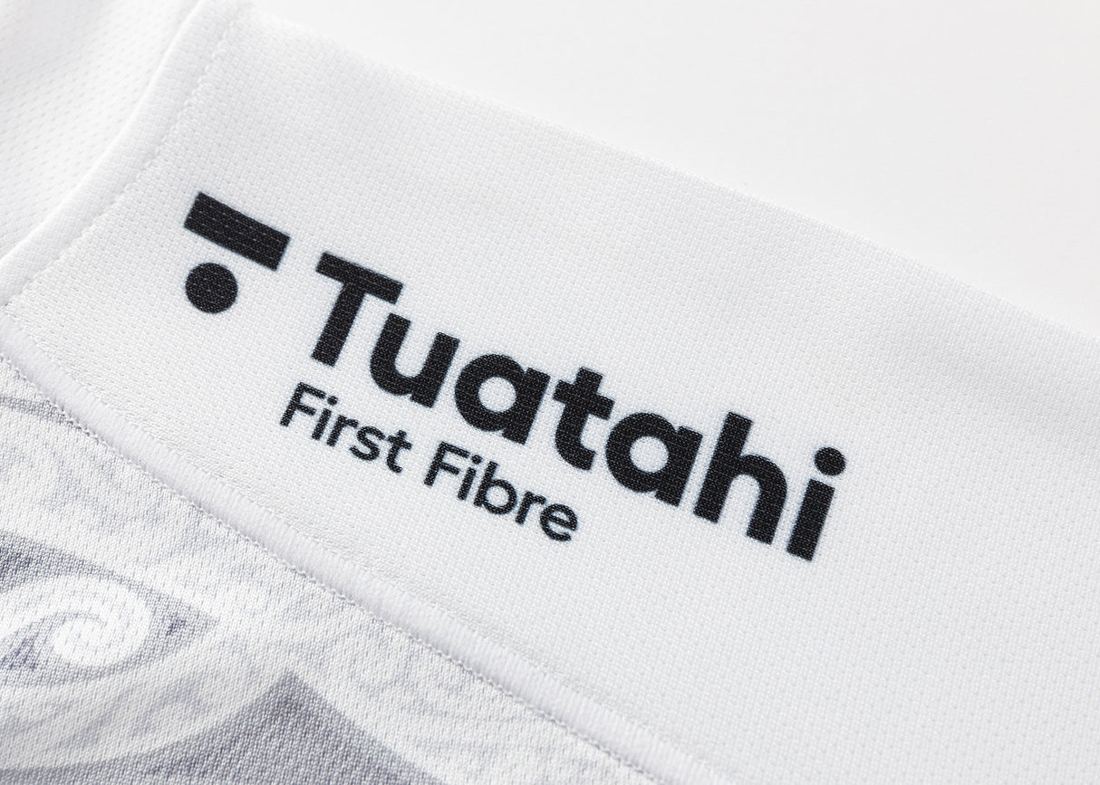 Close-up of a white fabric with black "Tuataki First Fibre" text, similar to the design on a Gallagher Chiefs Super Rugby Replica Away Jersey 25/26 by Classic Sportswear.