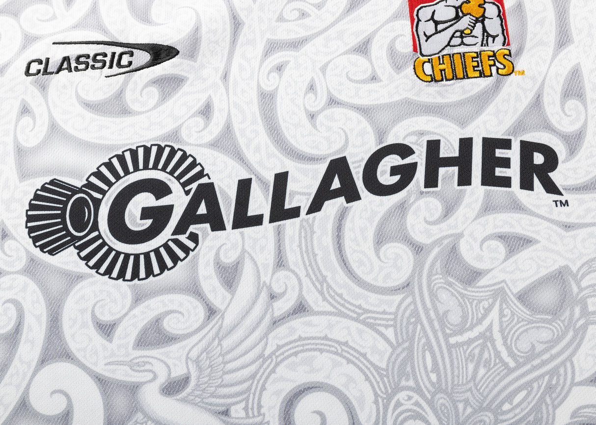 The Gallagher Chiefs Super Rugby Replica Away Jersey 25/26 by Classic Sportswear features iconic team logos on a stylish white and gray paisley pattern, embodying the spirit of Super Rugby.